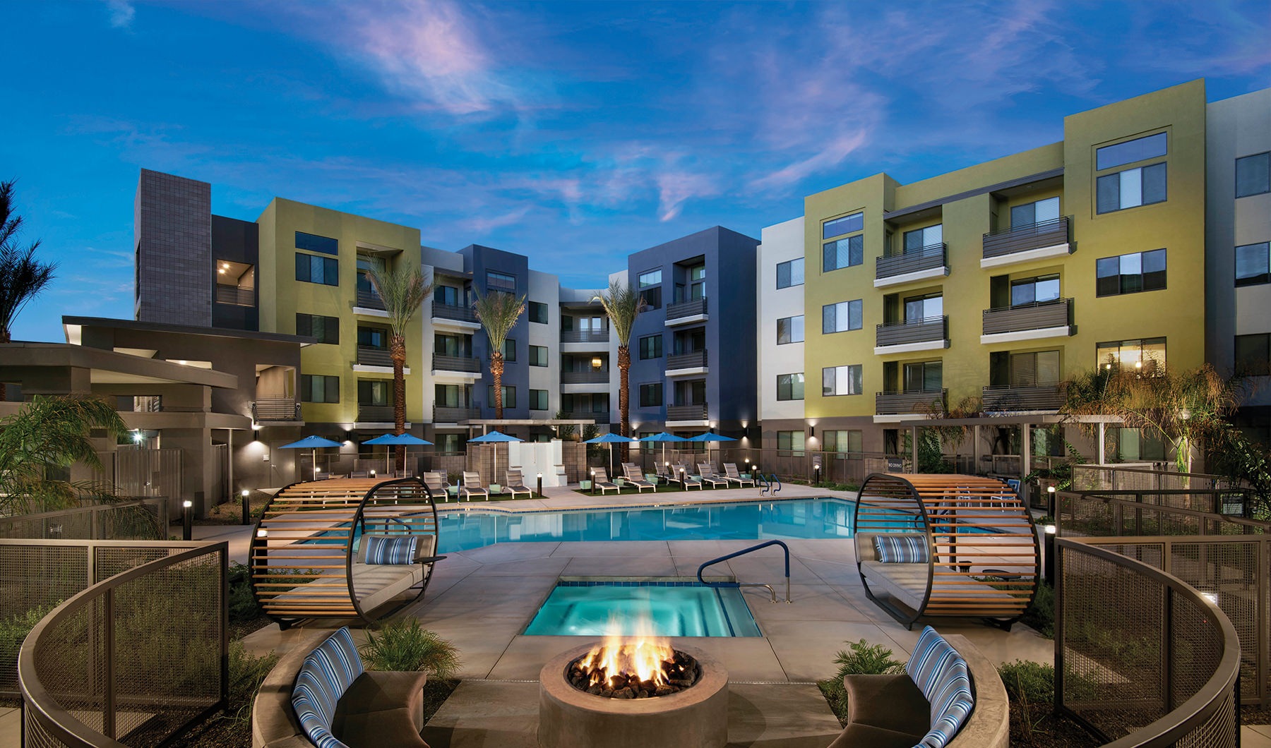 Resort-style swimming pool and hot tub surrounded by four story apartments